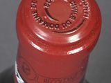 a close up of a bottle of wine with a red cap