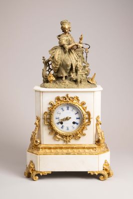 a white and gold clock with a statue on top of it