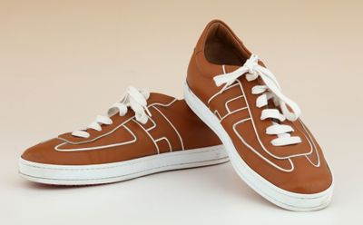 une paire de baskets marron avec des lacets blancs sur fond beige