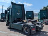 several green semi trucks parked in a parking lot with a blue sky in the background