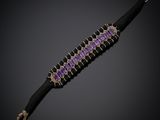 un gros plan d'un bracelet violet et noir sur fond noir