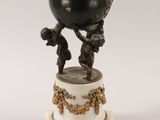 an image of a statue of a man holding a ball on top of a pedestal