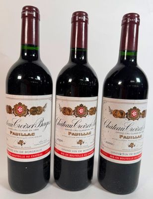 three bottles of red wine are lined up on a white surface