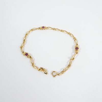 a gold bracelet with garnets and stones on a white background
