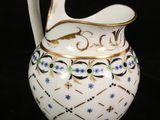 a white pitcher with blue flowers on it on a black background