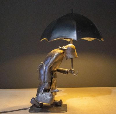 a statue of a man holding an umbrella on a table