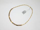 un collier en or posé sur une surface blanche, avec une étiquette de prix