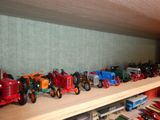 many toy tractors lined up on a shelf in a room