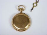 a gold pocket watch and a key on a white surface