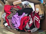 une boîte en carton remplie de vêtements et de chaussures posée par terre