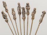 six antique silverware figurines on sticks in a glass vase