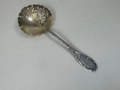 une cuillère en argent ornée d'une fleur sur une surface blanche