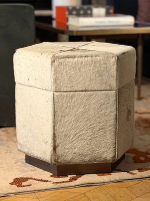 a small ottoman sitting on a rug in a living room