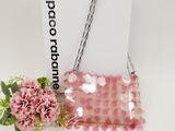a pink purse with a chain hanging from it next to a pink flower