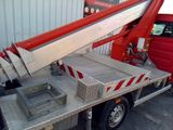 a red truck that has a large knife on the back of it