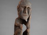 a wooden statue of a man with his hands on his face