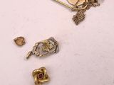 Plusieurs bijoux en or et en argent sont posés sur une surface blanche.