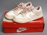 des baskets Nike Dunk Low roses et blanches posées sur une boîte rouge