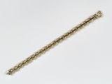 gros plan d'un bracelet en or sur une surface blanche