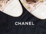 pair of chanel shoes sitting on top of a black bag on a wooden floor