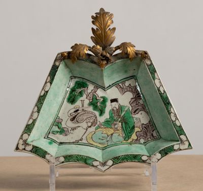 a green and white plate with a gold leaf decoration on it