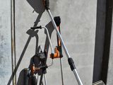 an orange and black drill on a tripod in front of a building