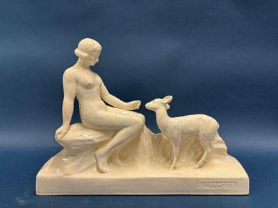 une image représentant une statue d'une femme assise sur un rocher avec une chèvre