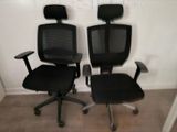 une paire de fauteuils de bureau noirs avec accoudoirs et dossiers dans une pièce