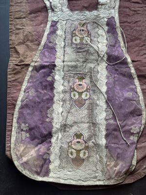 un vieux sac à main violet et blanc orné de fleurs, posé sur une table