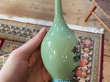 a person holding a vase in their hand on a rug