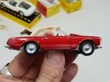 a person holding a red toy car in their hand