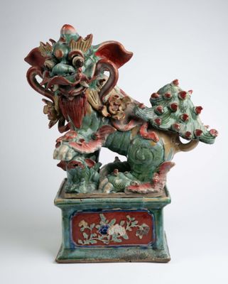 statue d'un dragon posée sur un socle, sur fond blanc