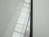 a picture of a mirror on the wall with the reflection of a building in it