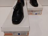 une paire de chaussures en cuir noir pour homme posée sur des cartons