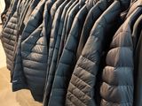 many jackets hanging on a rack in a store
