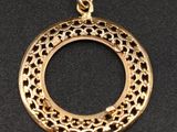un pendentif plaqué or présentant un motif circulaire sur fond noir