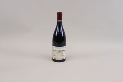 une bouteille de vin rouge posée sur une table blanche
