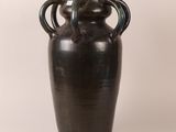 a black vase with two handles sitting on a white surface