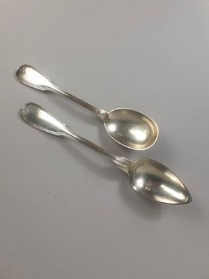deux cuillères en argent posées sur une table l'une à côté de l'autre