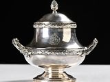 an antique silverplated sugar dish with a lid on a white table