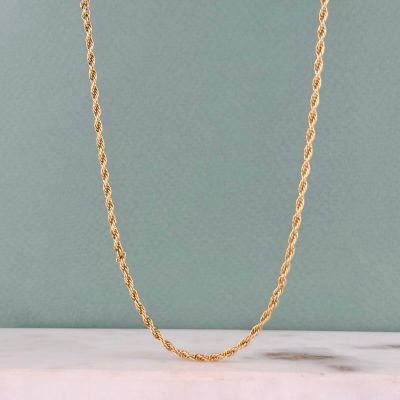 un collier à chaîne en or posé sur une surface en marbre