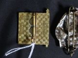 a small gold purse and a gold brooch on a black cloth