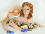 a doll sitting on the ground with a hat and other items