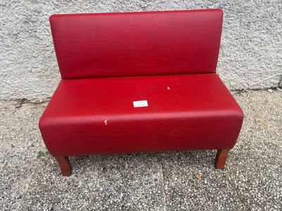 a red bench sitting on top of a sidewalk next to a cement wall