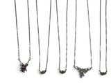 many different necklaces and pins on a white surface