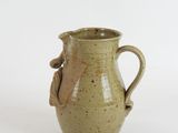 a small green vase with a handle on a white surface