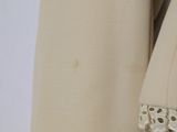 a close up of a beige coat with lace on the sleeves