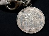 a silver coin on a chain with a chain around it