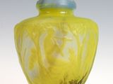 un vase jaune avec un couvercle bleu posé sur une surface blanche