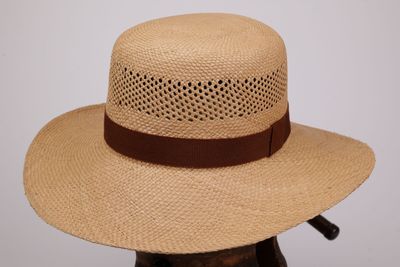 Le chapeau est en paille et est orné d'un ruban marron autour du bord.